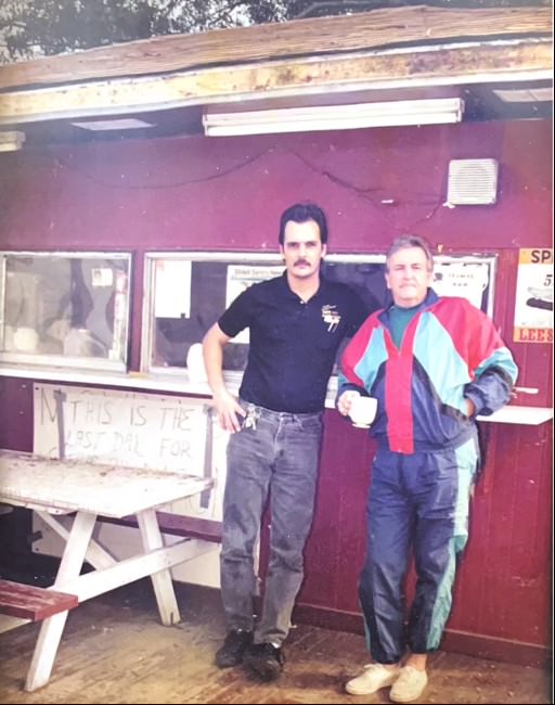 Two men standing outside the original Lee's Hamburgers walk-up window