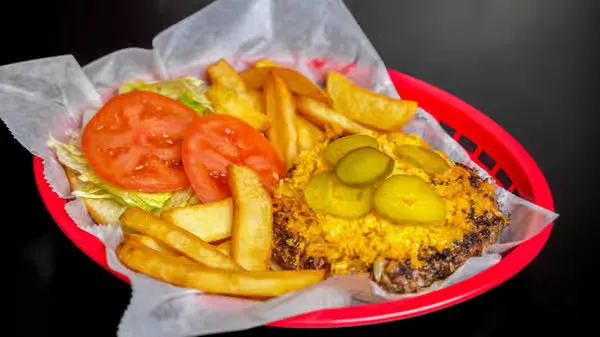 Open faced hamburger with melted cheese and condiments with fries in basket